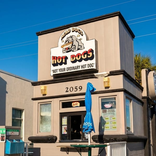 Mad Dogs Hot Dogs restaurant exterior with a bulldog logo, blue umbrella, and street number 2059.
